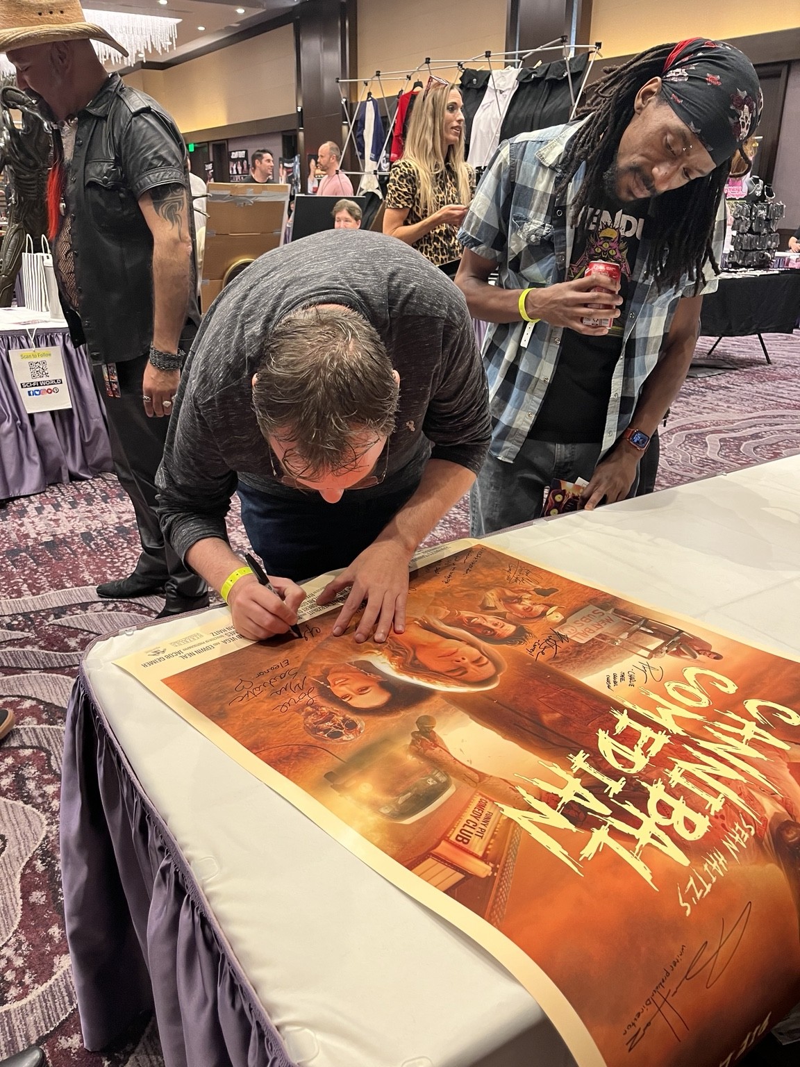 Event attendee signing a horror film poster